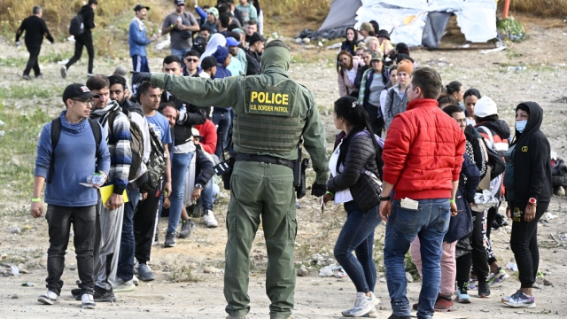A U.S. Border Patrol agent directs asylum-seekers waiting between the double fence along the U.S.-Mexico border near Tijuana.