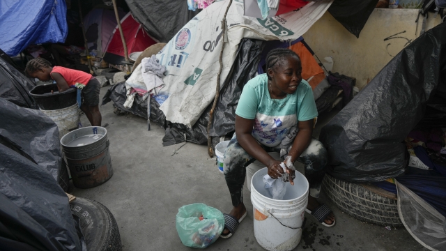 A Haitian migrant washes clothes at a makeshift shelter