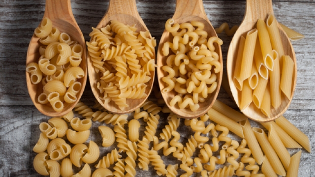 Various types of pasta on wooden spoons.