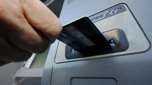 A person inserts a debit card into an ATM