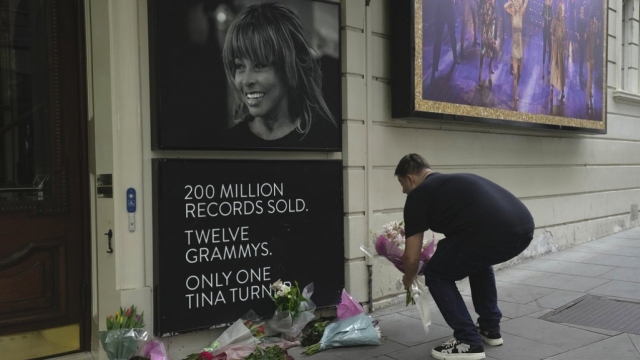 A man places flowers at a memorial for Tina Turner outside Aldwych Theatre in London.