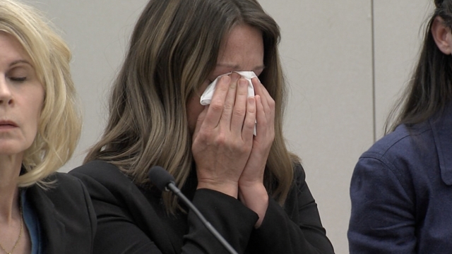 Dr. Caitlin Bernard holds tissue to face during hearing.
