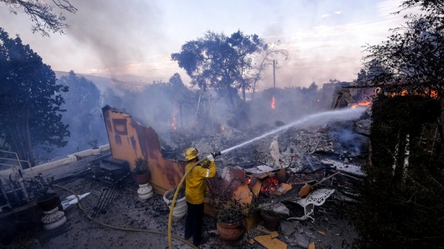 A firefighter tries to extinguish the flames at a burning house as the South Fire burns in Lytle creek.