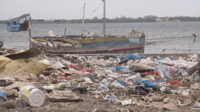 Plastic waste seen on the coast of a body of water with boats
