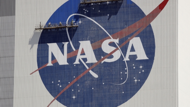 Workers on scaffolding repaint the NASA logo.