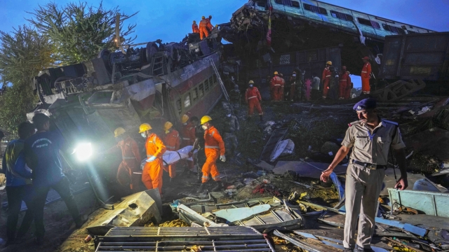 People inspect the site of passenger trains that derailed in India