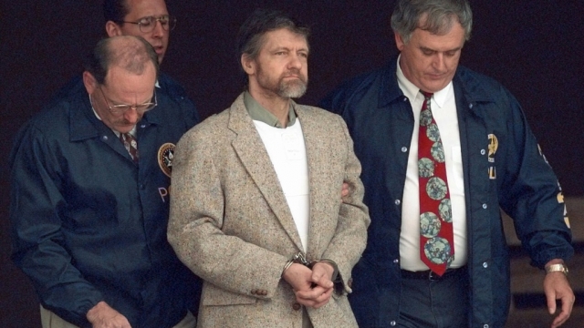 Theodore 'Ted' Kaczynski looks around as U.S. Marshals prepare to take him down the steps at the federal courthouse