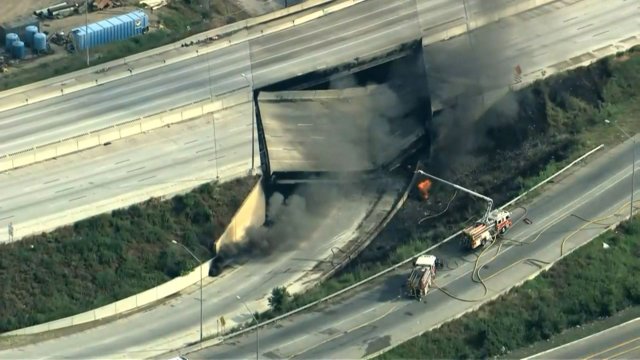 A collapsed section of Philadelphia's I-95 is seen on fire with smoke rising from the roadway.