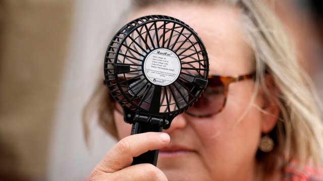 A Houston Astros fan uses a hand fan to keep cool.