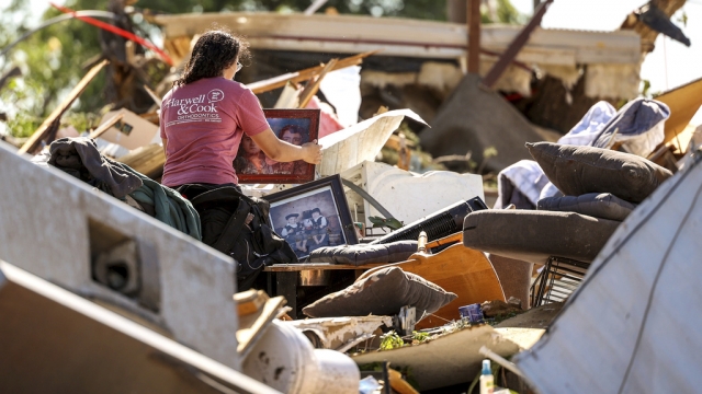 A woman sifts through a tornado damaged home.