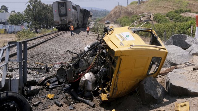 A destroyed truck lies next to a derailed Amtrak train.