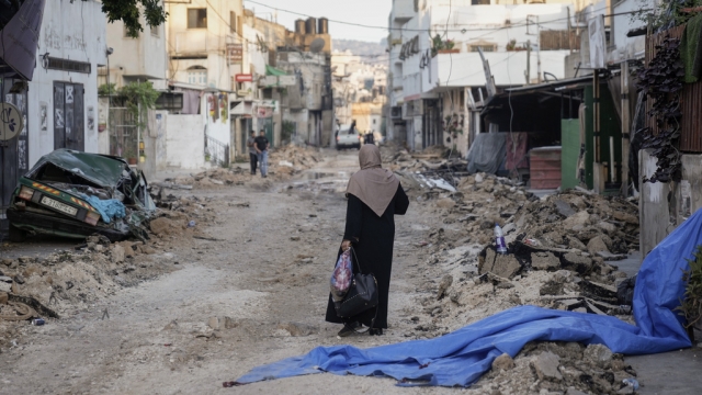 Palestinian woman walks on a damaged road in the Jenin refugee camp in the West Bank.