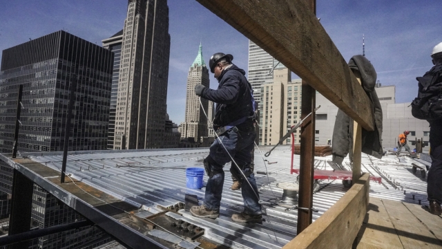 Construction workers install roofing on a high rise in Manhattan's financial district.