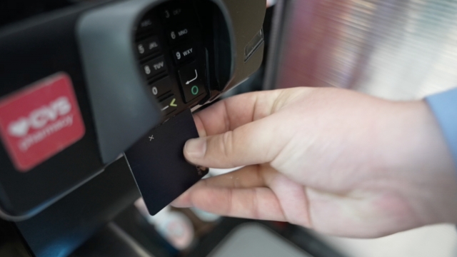 Hand pushes credit card into chip slot during payment transaction.