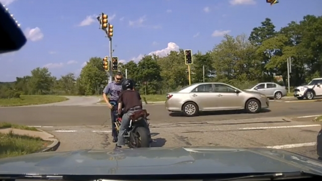 A police officer pulls over a motorcycle driver.