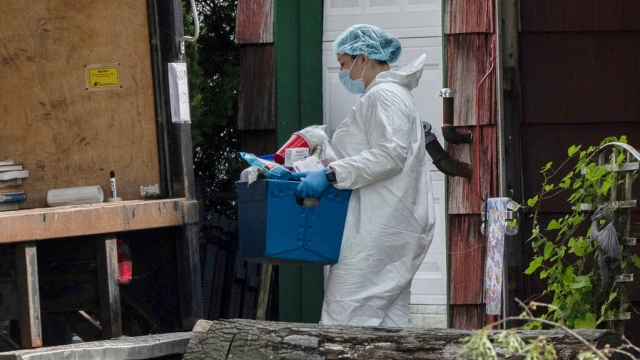 A crime laboratory officer removes a box of items as law enforcement searches the home of Rex Heuermann.