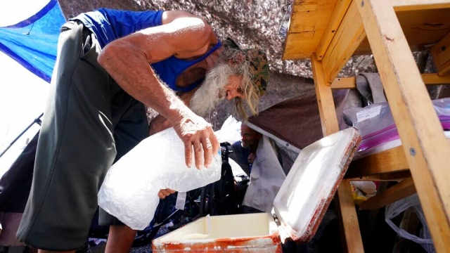 A homeless man places a bag of ice in a cooler in Arizona