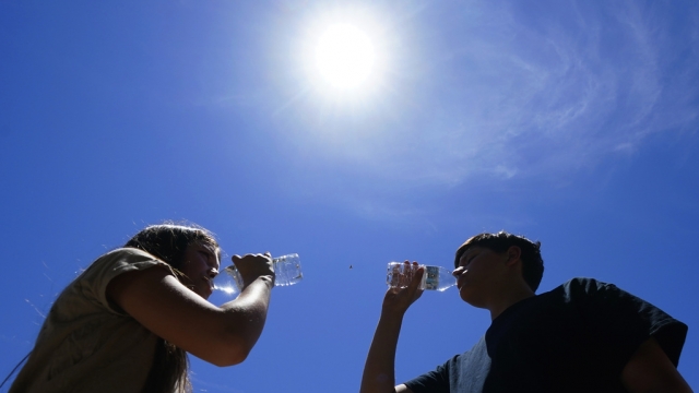 People drinking water under the hot sun.