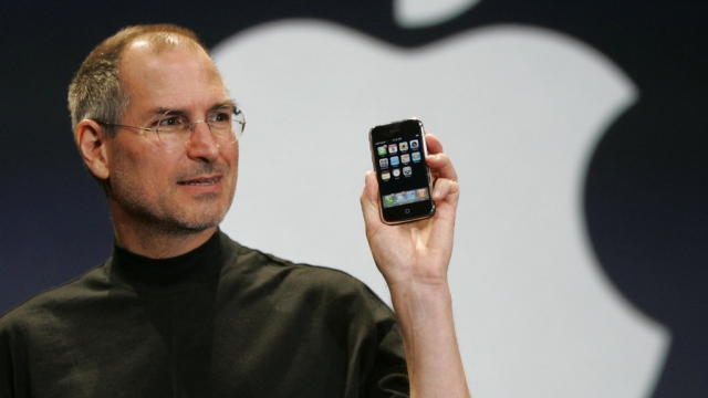 Former Apple CEO Steve Jobs holds up the first-generation iPhone.