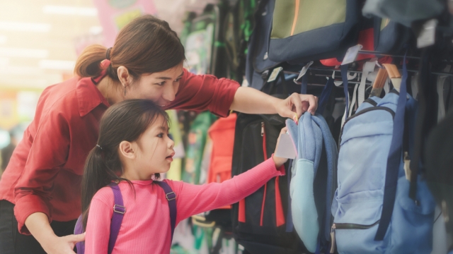 Family shops for backpacks in a store.