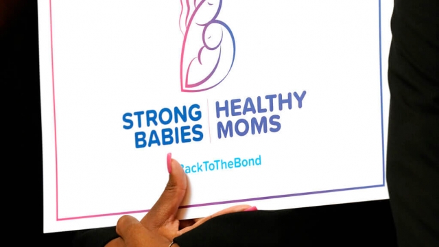 An event attendee holds a sign supporting postpartum care