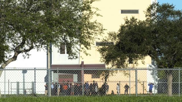 Nine members of Congress and others wait to enter Marjory Stoneman Douglas High School.