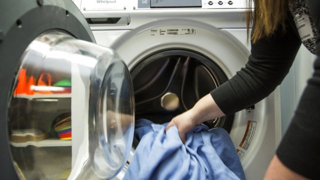 A person puts laundry in a washing machine.