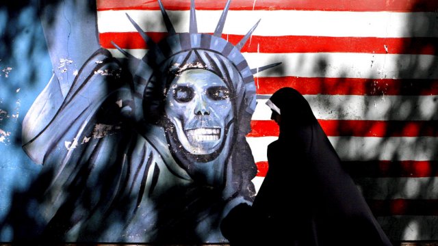 An Iranian woman walks past graffiti art characterizing the U.S. Statue of Liberty, painted a wall in Tehran.