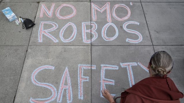 Person writes a message in chalk opposing a proposed robotaxi expansion in San Francisco.