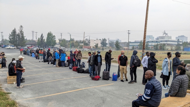 People without vehicles line up to register for evacuation flights in Yellowknife, Canada