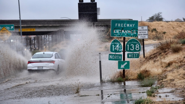 A vehicle drives through a flooded freeway entrance in Palmdale, California.