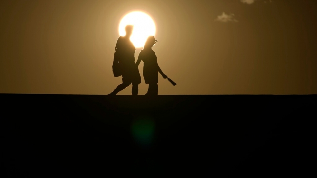 People walk along a trail as the sun sets.