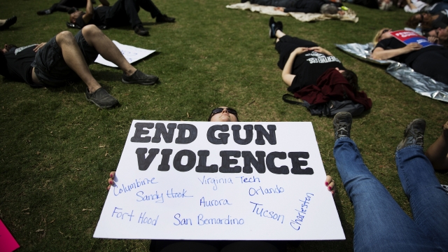 Someone holds a sign during a "die-in" protest against the National Rifle Association's annual convention
