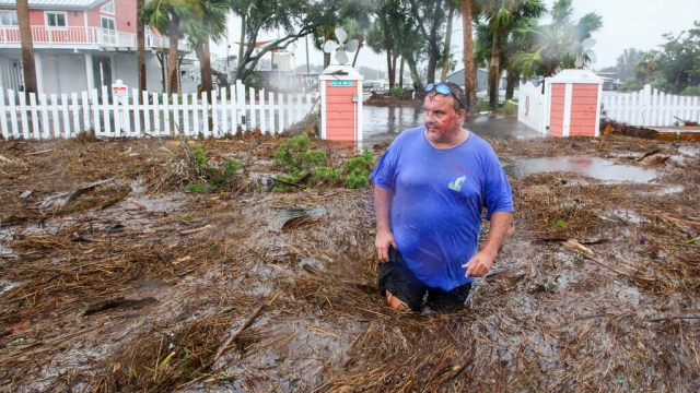 Daniel Dickert wades through debris in floodwater in front of his Florida home