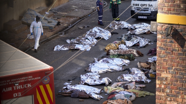 Medics stand by the covered bodies of victims of a deadly blaze in downtown Johannesburg.