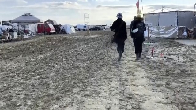 People walk along a muddy path at the Burning Man festival site.