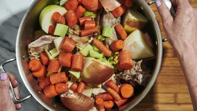 A pot with onions, carrots and chicken bones