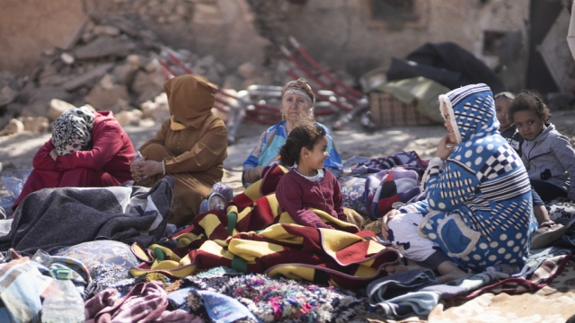 Families sit outside their destroyed homes after an earthquake in Moulay Brahim.