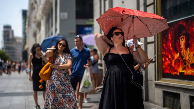 A woman holds an umbrella to shelter from the sun during a hot sunny day in Madrid, Spain.