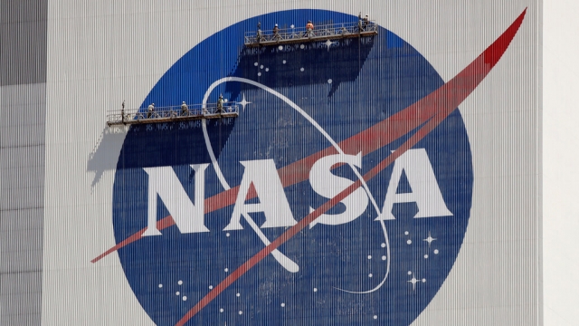 Workers maintain the NASA logo on a building