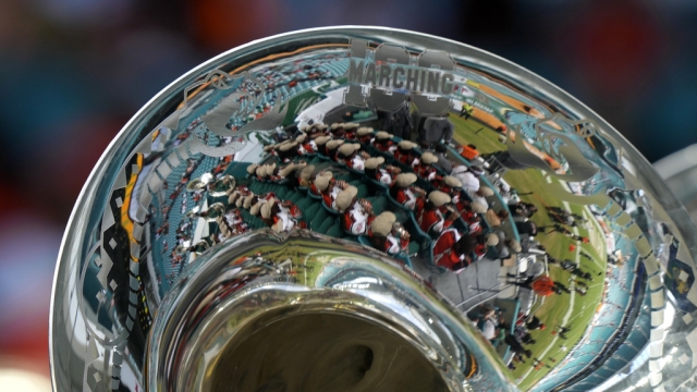 The image of a marching band reflects off an instrument