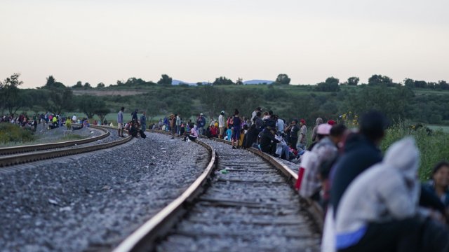 Migrants walk along a train track.