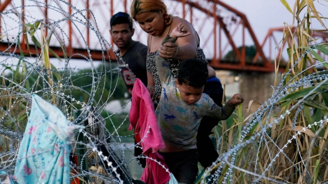 Migrants climb over concertina wire after they crossed the Rio Grande and entered the U.S. from Mexico.