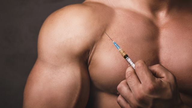 Muscular man holding a syringe