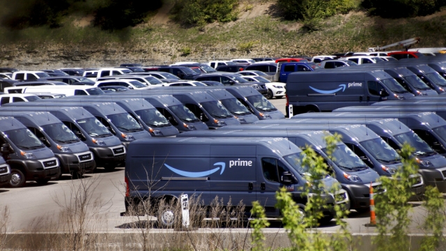 Rows of Amazon Prime delivery vans are stored in a parking lot