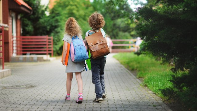 Stock photo of two children walking while wearing backpacks.