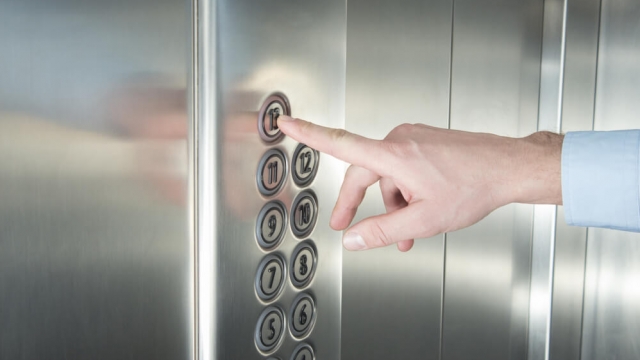 A person pressing the 13th floor button in the elevator.