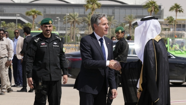 U.S. Secretary of State Antony Blinken shakes hands with a Saudi official before boarding a plane