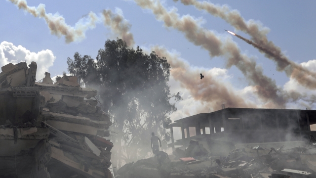 Rockets are fired from the Gaza Strip toward Israel over destroyed buildings