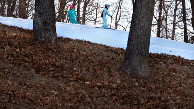 Skiers ride on a trail made of completely machine-made snow in February 2023 as warmer temperatures led to less snow.
